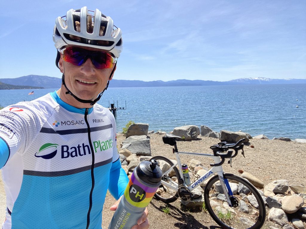 Jonathan Moore standing with water bottle next to his bike and the ocean