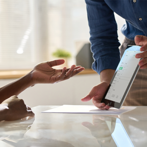 Sales rep presents a digital roofing contract to a homeowner at the kitchen table