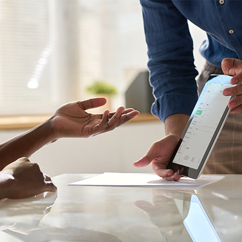 Sales rep presents a digital roofing contract to a homeowner at the kitchen table